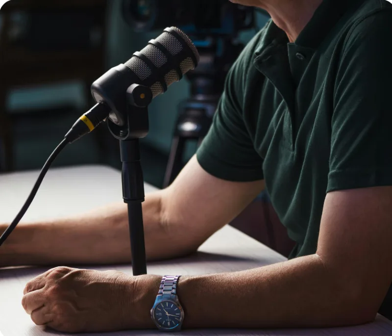 Ein Mann sitzt entspannt vor einem Podcast-Mikrofon